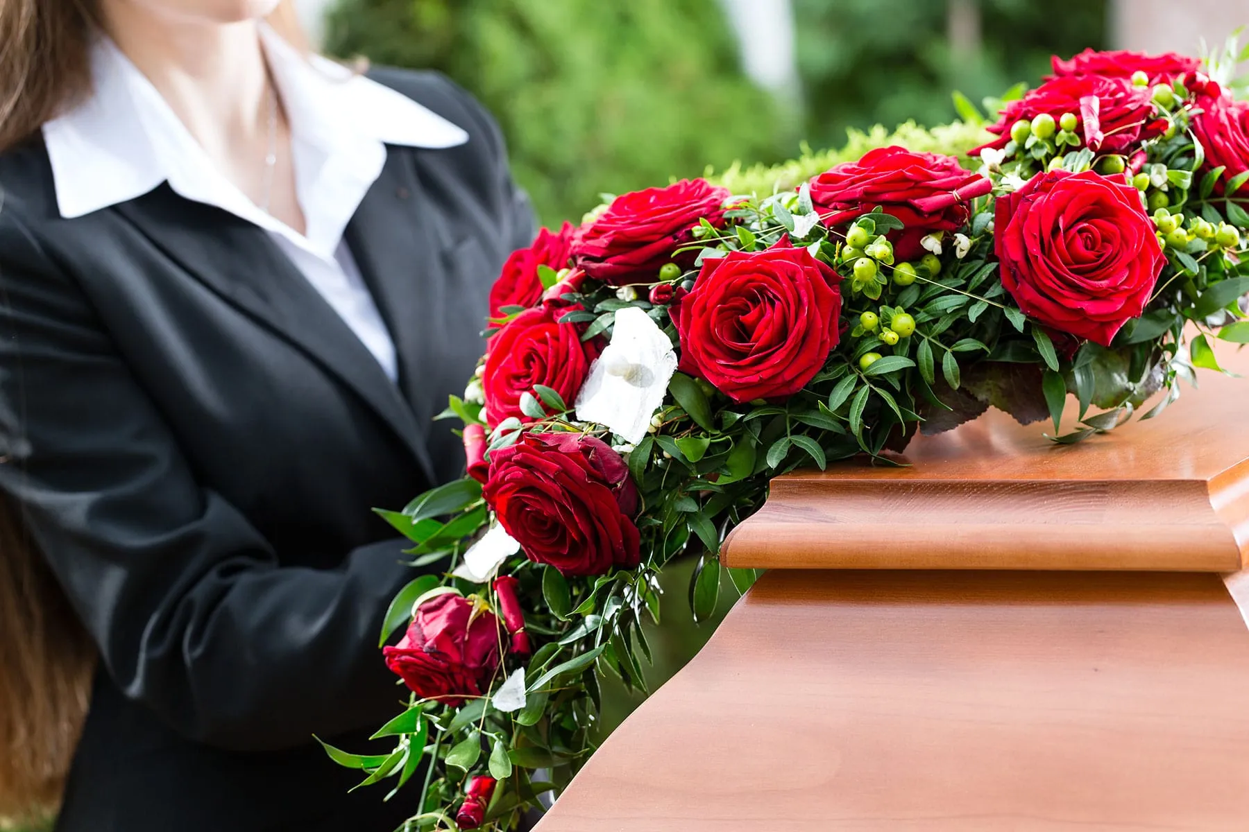 Composition florale de roses rouges et de feuillage posée sur un cercueil